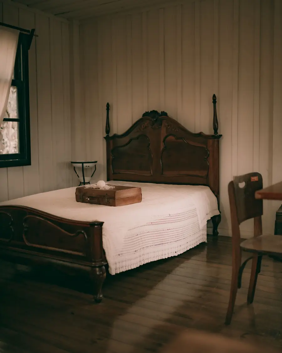 Cama de madeira escura em quarto com paredes de madeira e piso de tábua